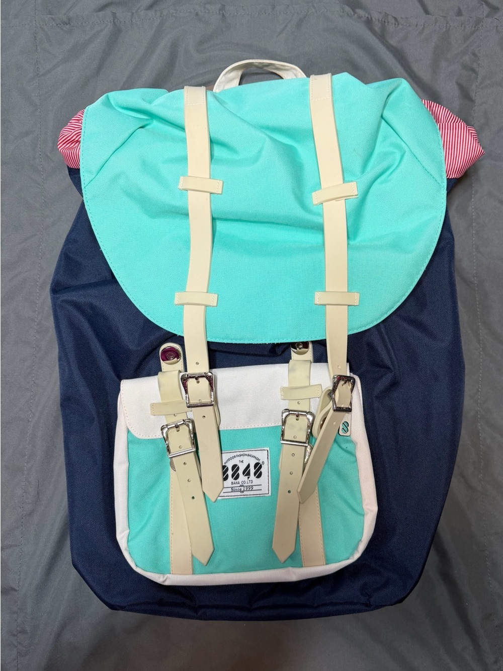 BANA COLTO branded backpack featuring a top flap with buckle straps